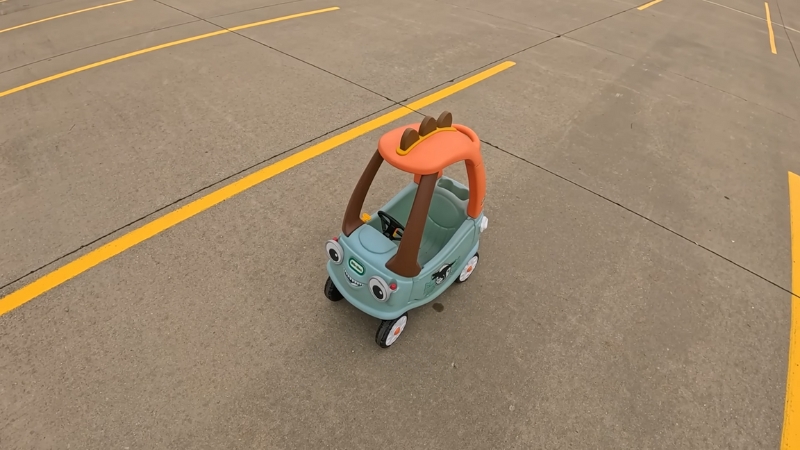 Little Tikes Cozy Coupe Tractor toy parked on a concrete surface with yellow parking lines