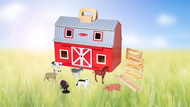 Melissa & Doug wooden farm barn set with toy animals, fences, and a red barn placed in a grassy field